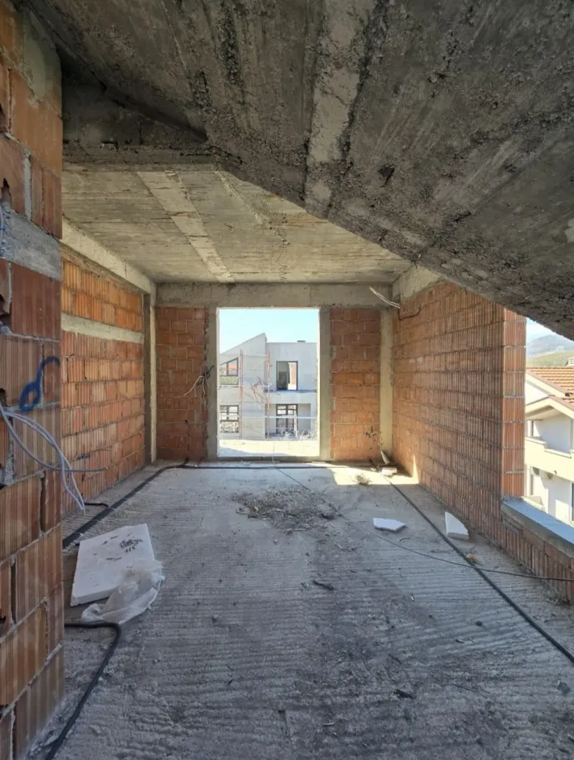 Unutrašnjost prostorije u izgradnji sa betonskim plafonom i ciglenim zidovima.