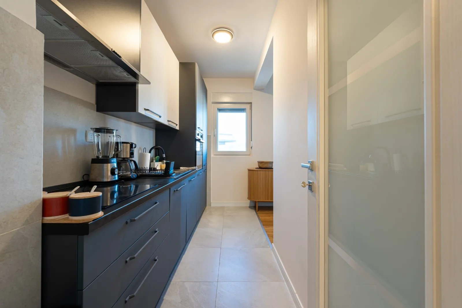 Modern narrow kitchen with dark lower cabinets and white upper cabinets.