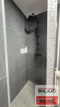 Tuš kabina sa tamnim pločicama i crnim tušem. - image 12