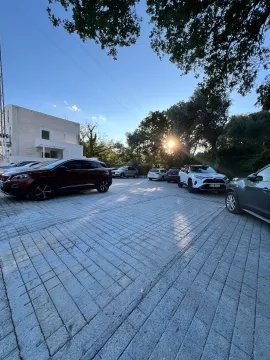 Paved parking area in front of an apartment building with parked cars. - image 6