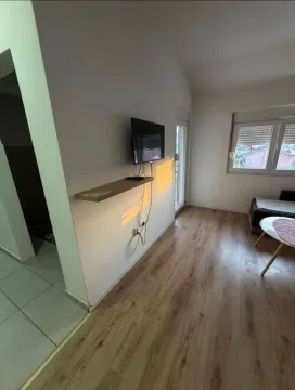 Living room with wooden flooring, wall-mounted TV, and a window. - image 3