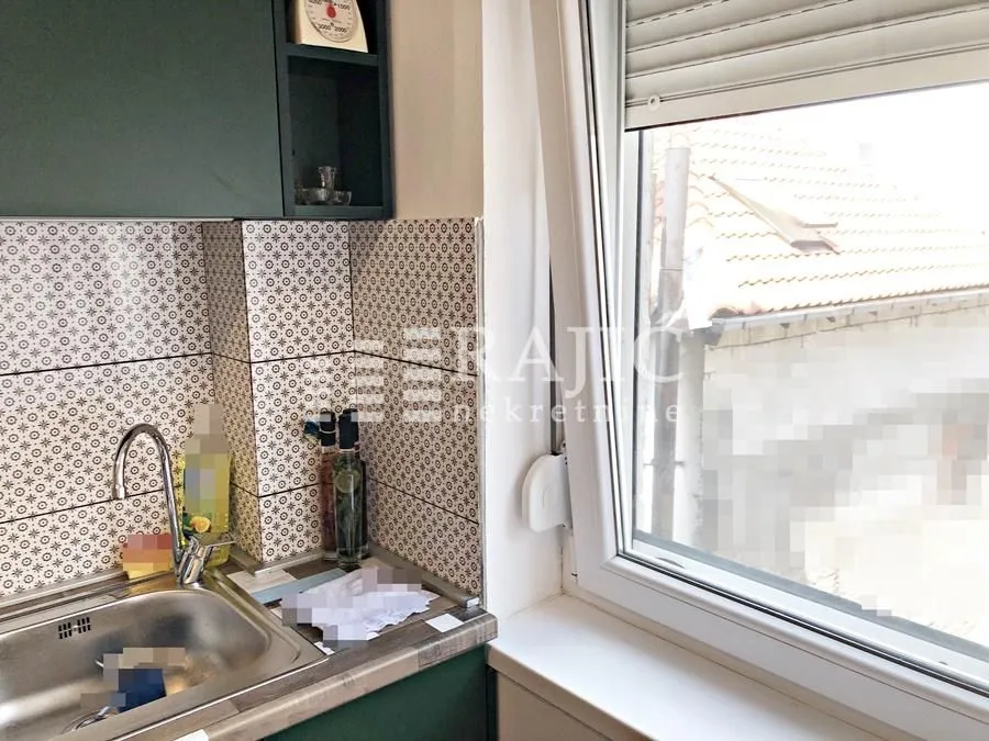 Part of the kitchen with a sink and a view through the window.