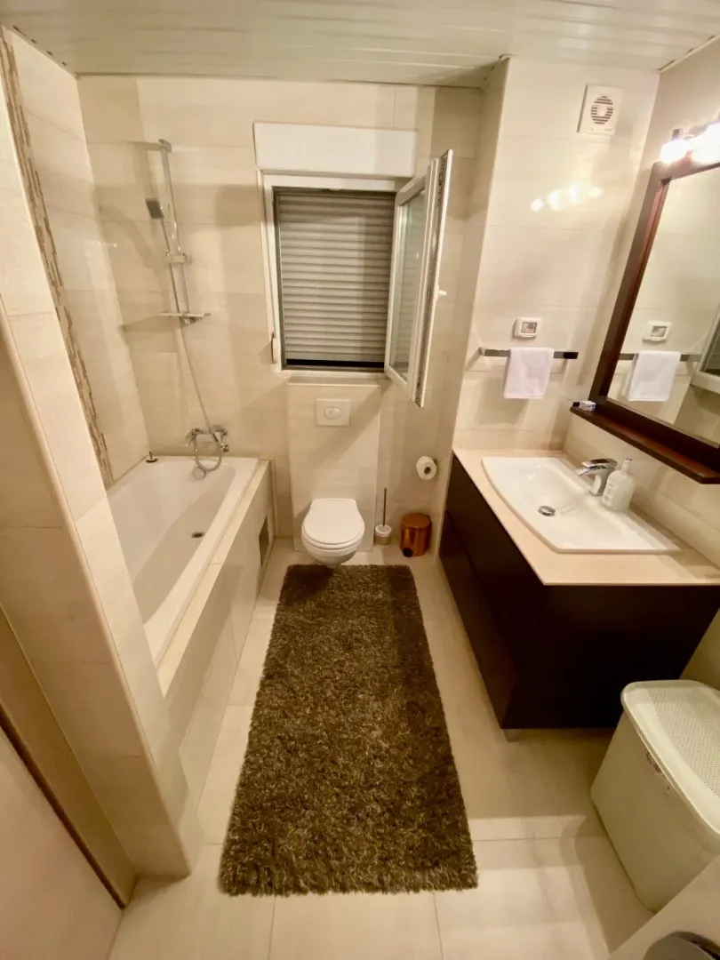 Modernly equipped bathroom with a bathtub, washbasin, and toilet.