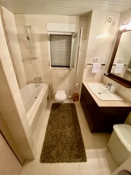 Modernly equipped bathroom with a bathtub, washbasin, and toilet. - image 11