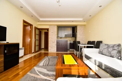 Living room with a sofa, TV unit, and a dining area in the background. - image 4