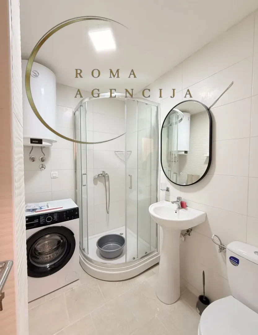 Brightly equipped bathroom with a shower cabin, sink, and washing machine.