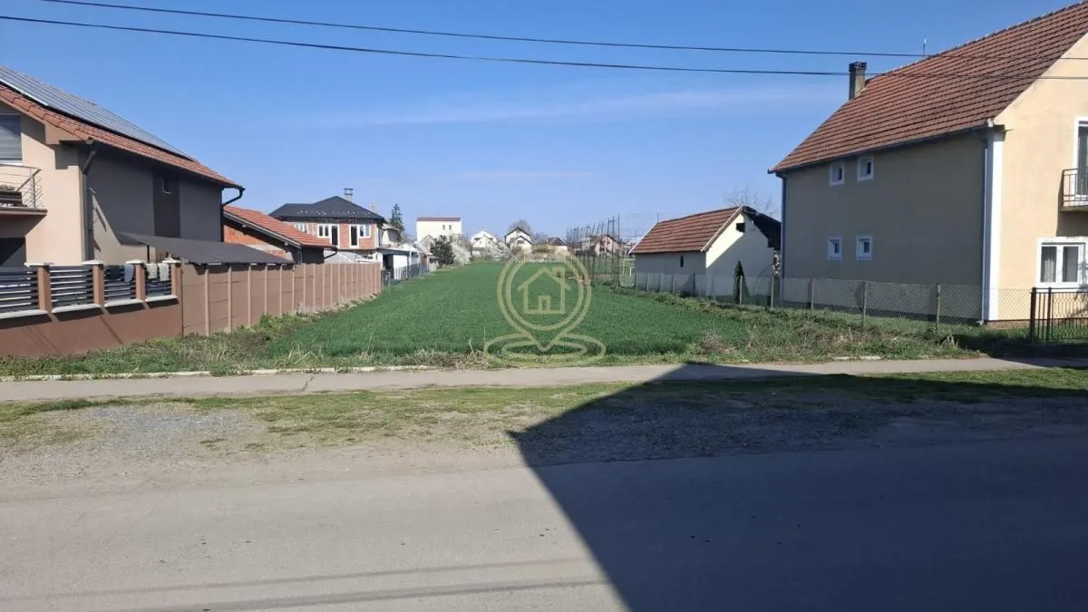 Pogled na praznu građevinsku parcelu između porodičnih kuća.