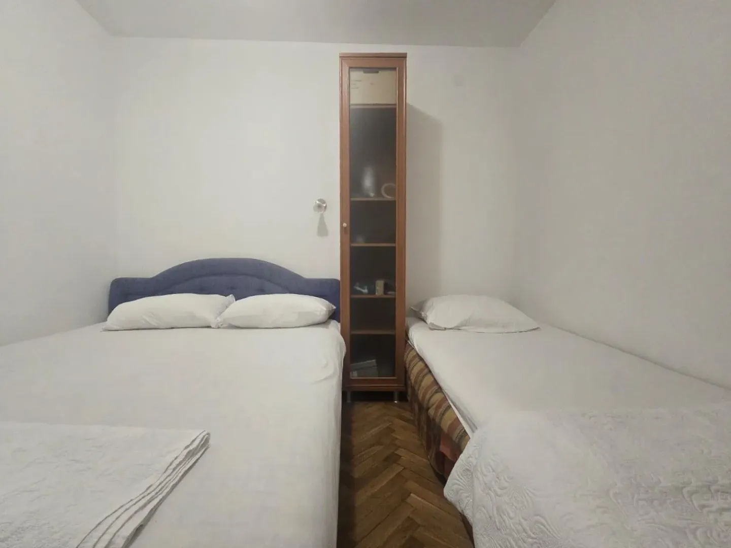 Bedroom with two beds and a wooden display cabinet.