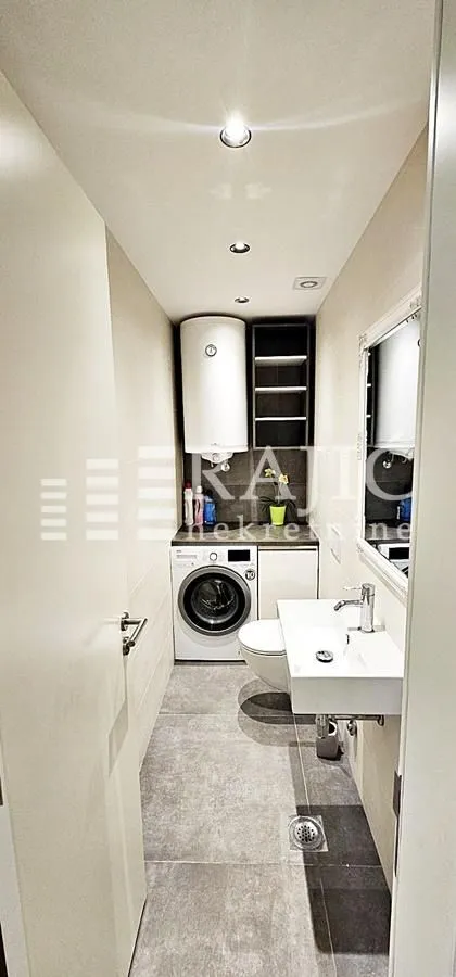 Smaller bathroom with a sink, toilet, and washing machine.