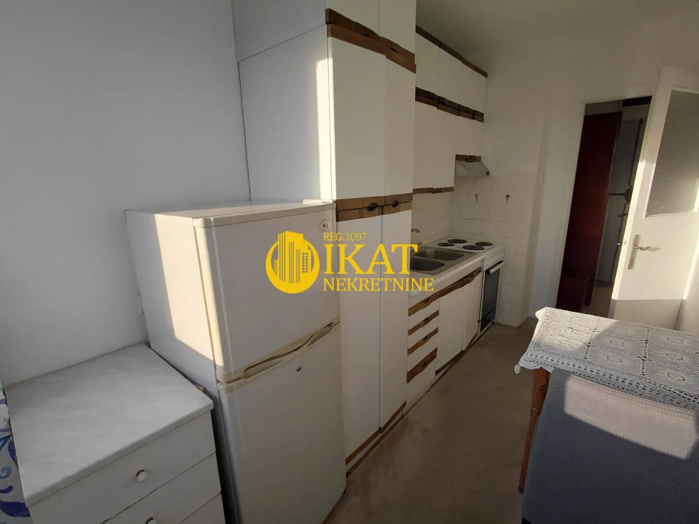 Smaller kitchen with white cabinets and a refrigerator.
