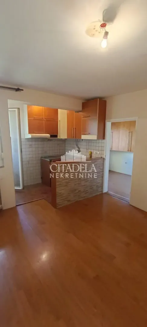 Manja kuhinja sa drvenim elementima i šankom.