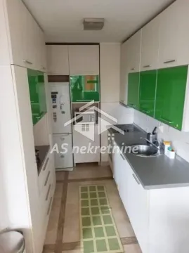 Small kitchen with white cabinets, green glass details, and a refrigerator. - image 6