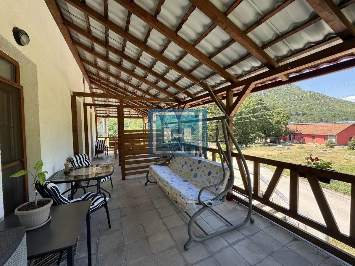 Covered terrace with a wooden structure, seating furniture, and a swing.