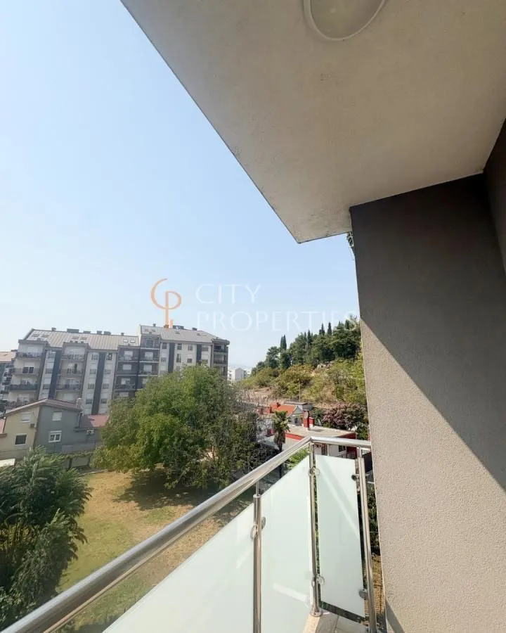 Pogled sa balkona na okolne zgrade i zelene površine.