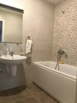 Kupatilo opremljeno umivaonikom, ogledalom i kadom sa mozaik pločicama na zidu. - image 9