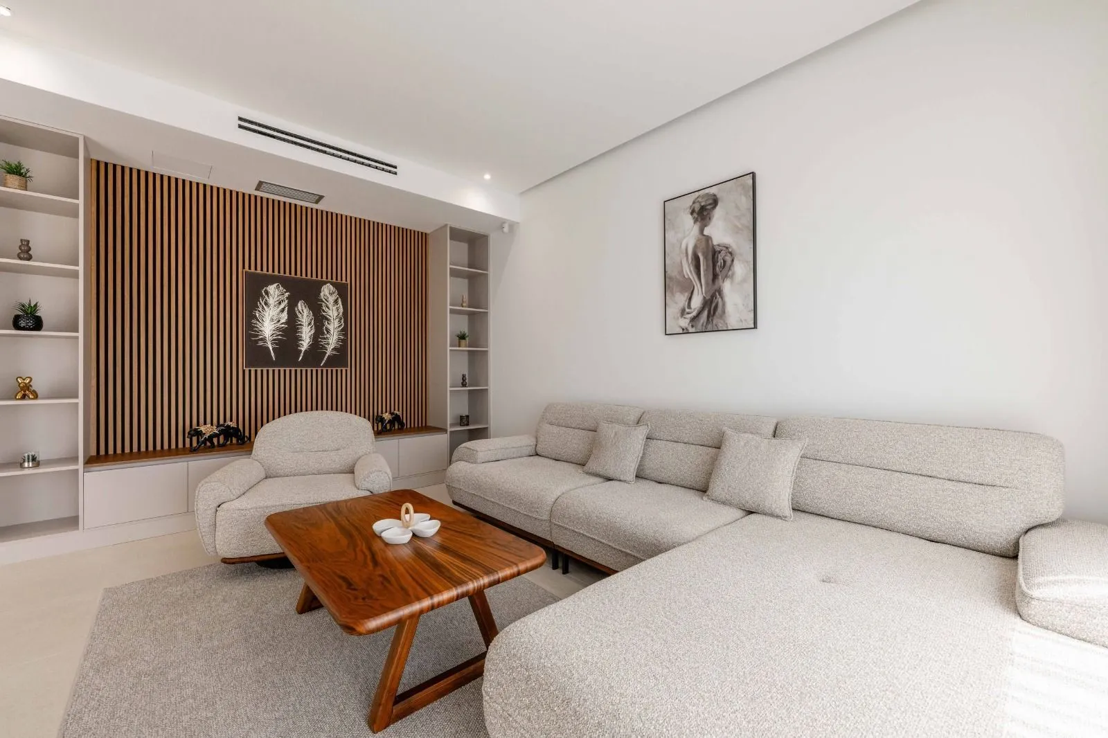 Living room with a sectional sofa, wooden coffee table, and decorative wall panels.