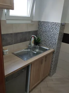 Kuhinjski ugao sa sudoperom i drvenim elementima ispod prozora. - image 21