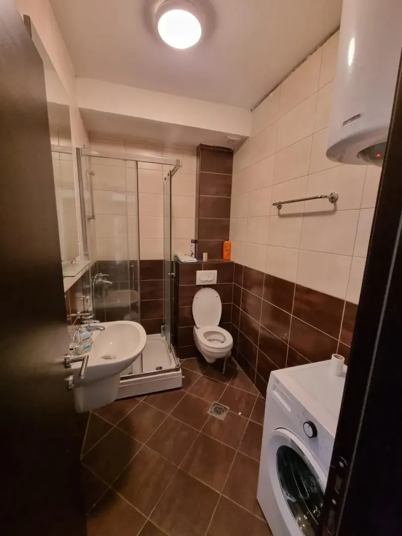 Manje kupatilo sa tuš kabinom, umivaonikom i veš mašinom.