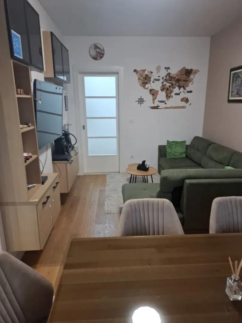 Dnevni boravak sa garniturom, trpezarijskim stolom i drvenim namještajem.
