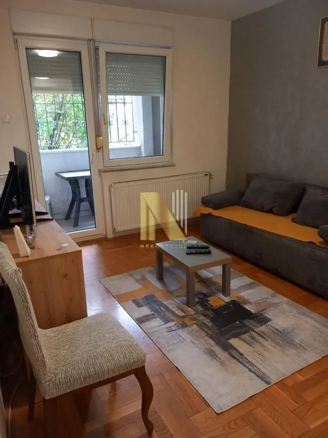 Dnevna soba sa garniturom, stočićem i izlazom na terasu.