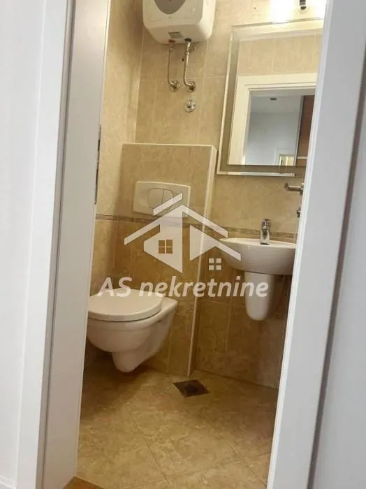 Pogled na kupatilo sa wc šoljom, umivaonikom i ogledalom.