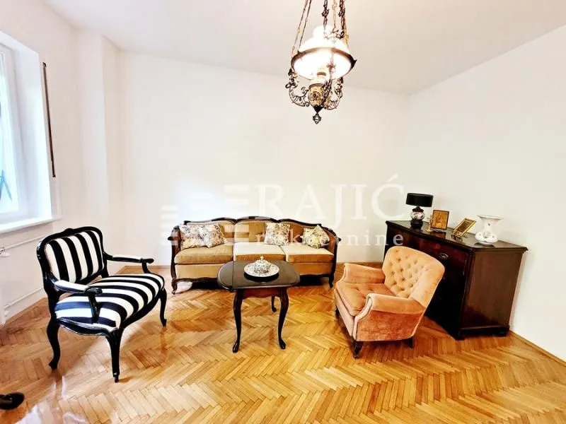 Living room with a sofa set, armchairs, and parquet flooring.