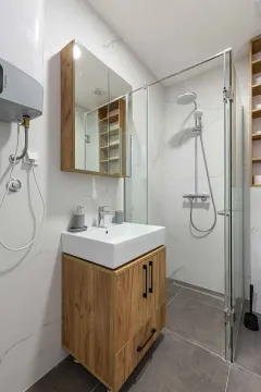 Moderne kupatilo sa umivaonikom, drvenim ormarićem i staklenom tuš kabinom. - image 6