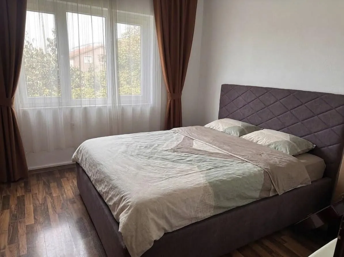 Bedroom with a large double bed and a window with curtains.