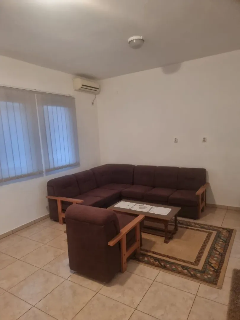 Dnevna soba sa ugaonom garniturom, foteljom i stočićem.