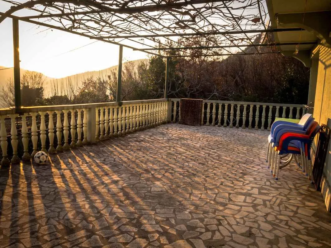 Prostrana terasa natkrivena vinovom lozom sa pogledom na okolinu.