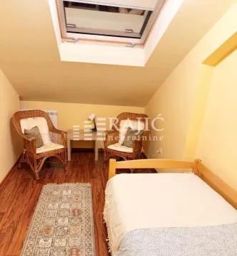 Attic bedroom furnished with a bed, wicker armchairs, and a roof window. - image 11