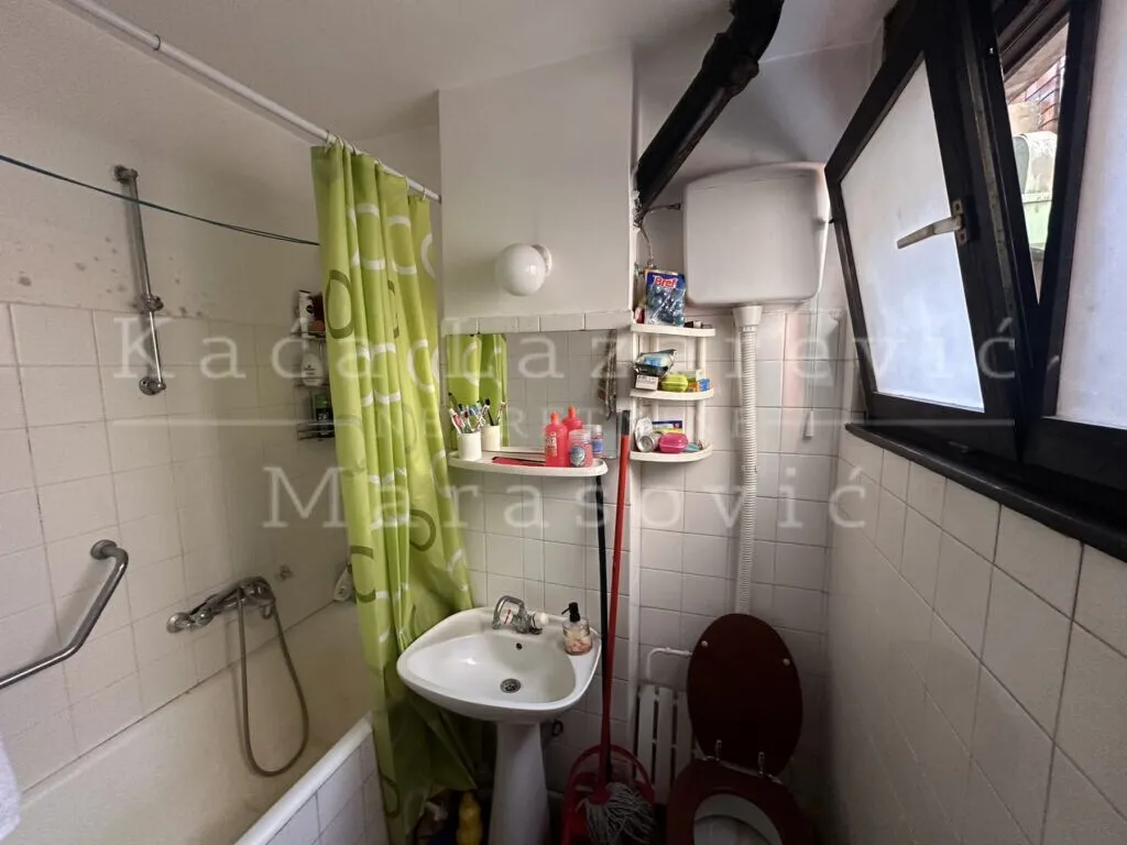 Manje kupatilo sa kadom, umivaonikom, wc šoljom i prozorom.