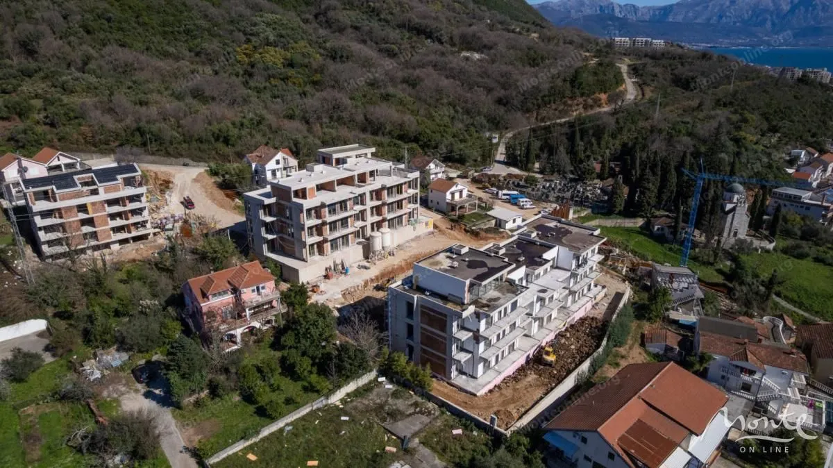 Pogled iz vazduha na stambene zgrade u izgradnji okružene zelenilom.