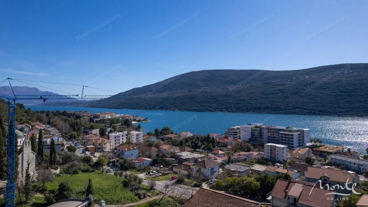 Pogled iz vazduha na zaliv, naselje i okolne planine.