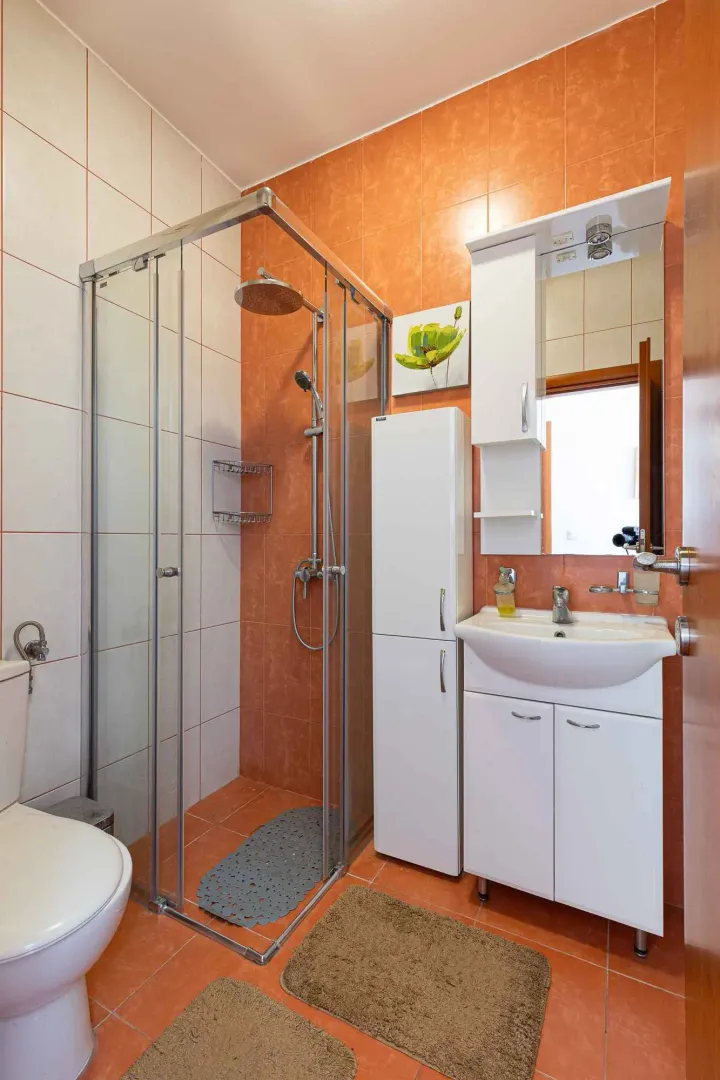 Kupatilo opremljeno tuš kabinom, umivaonikom i wc šoljom.