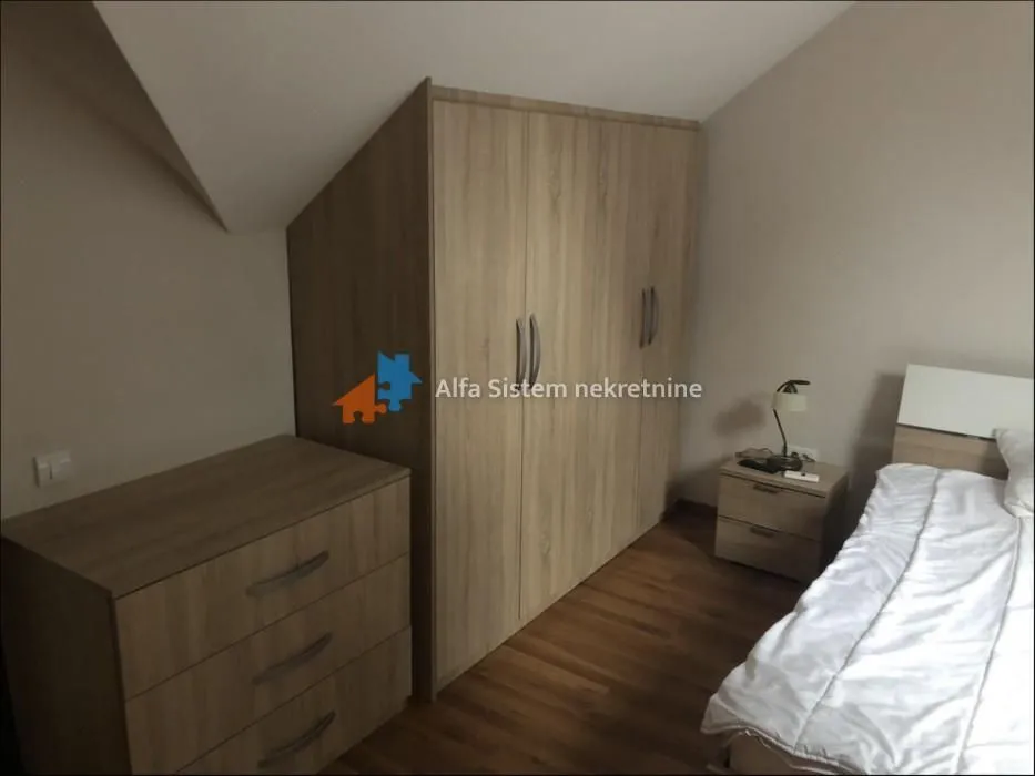 Furnished bedroom with a double bed, large wardrobe, and chest of drawers.