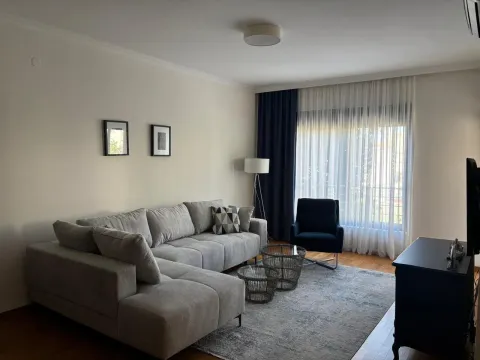 Living room with a sectional sofa, armchair, and a large window with curtains. - image 2