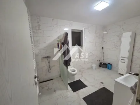 Spacious bathroom tiled with marble-pattern tiles, featuring a walk-in shower and toilet. - image 9
