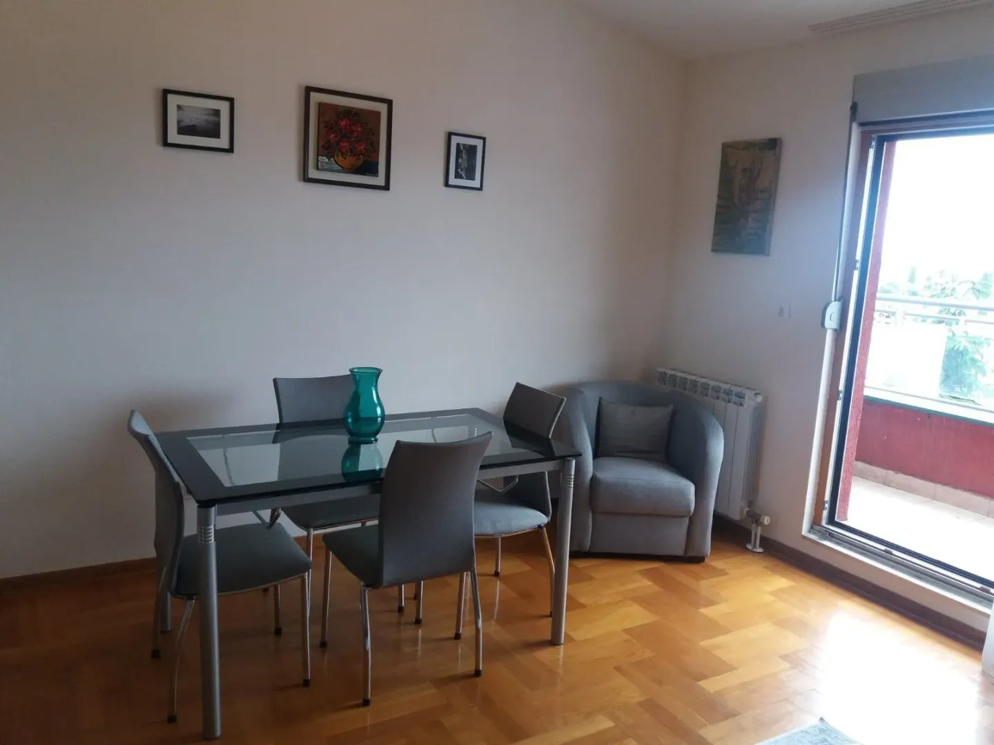 A dining table with chairs and a comfortable armchair next to balcony doors.