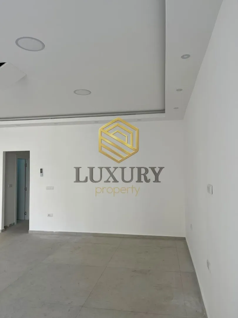 Empty bright room with white walls and tiled floors.
