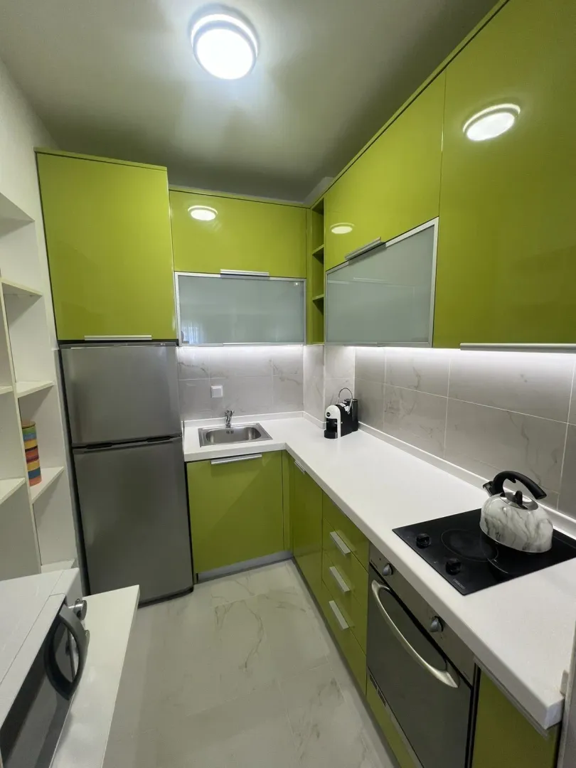 Bright kitchen featuring green cabinets and built-in appliances.