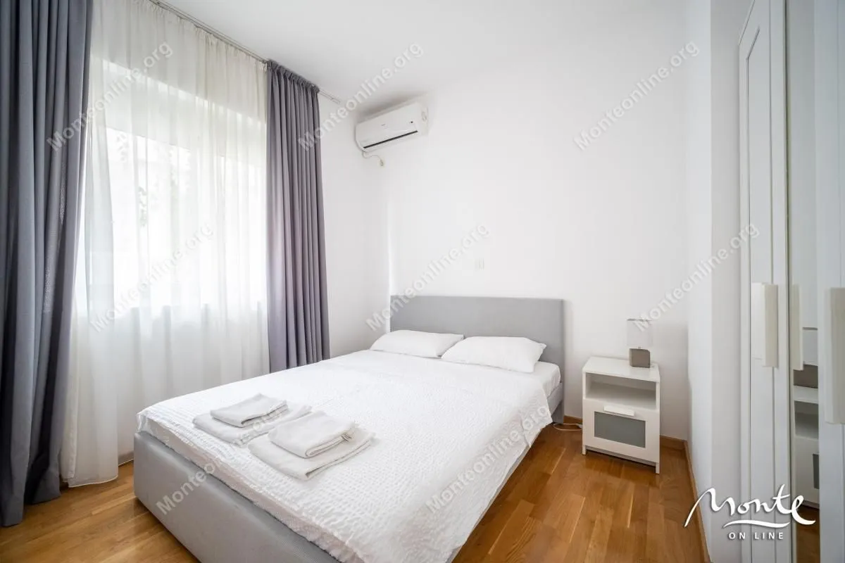 Svjetla spavaća soba sa bračnim krevetom, bijelom posteljinom i bijelim zidovima.