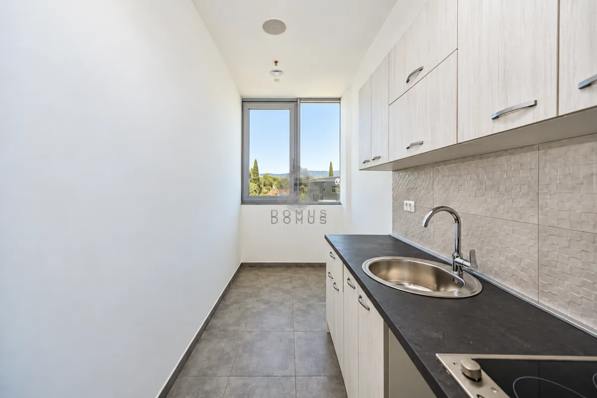 Smaller kitchen with light cabinetry and a window overlooking nature.