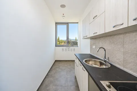Smaller kitchen with light cabinetry and a window overlooking nature. - image 6