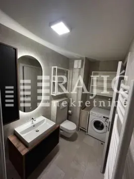 Modernly equipped bathroom with a washbasin, toilet, and washing machine. - image 17