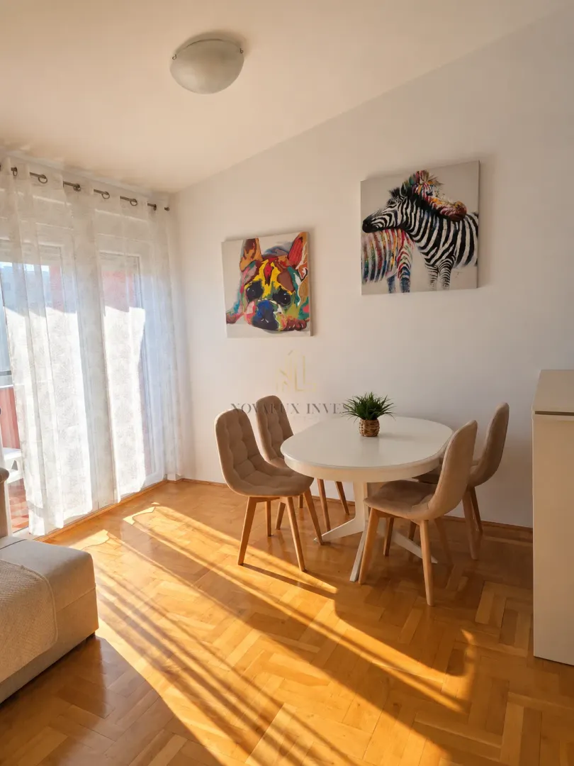 Living room with a dining table, chairs, and artwork on the wall.