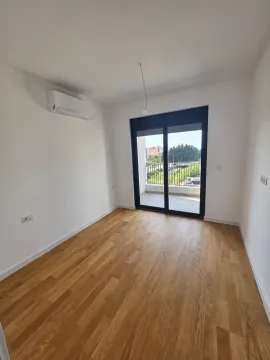 Prazna soba sa drvenim podom, klima uređajem i balkonskim vratima. - image 5