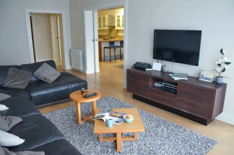 Living room with a sectional sofa, TV, and a view into the kitchen. - image 8
