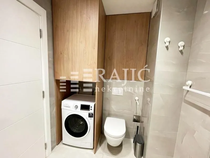 Modern bathroom with built-in cabinet, washing machine, and toilet.