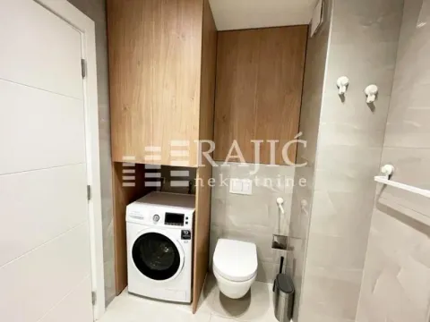 Modern bathroom with built-in cabinet, washing machine, and toilet. - image 7